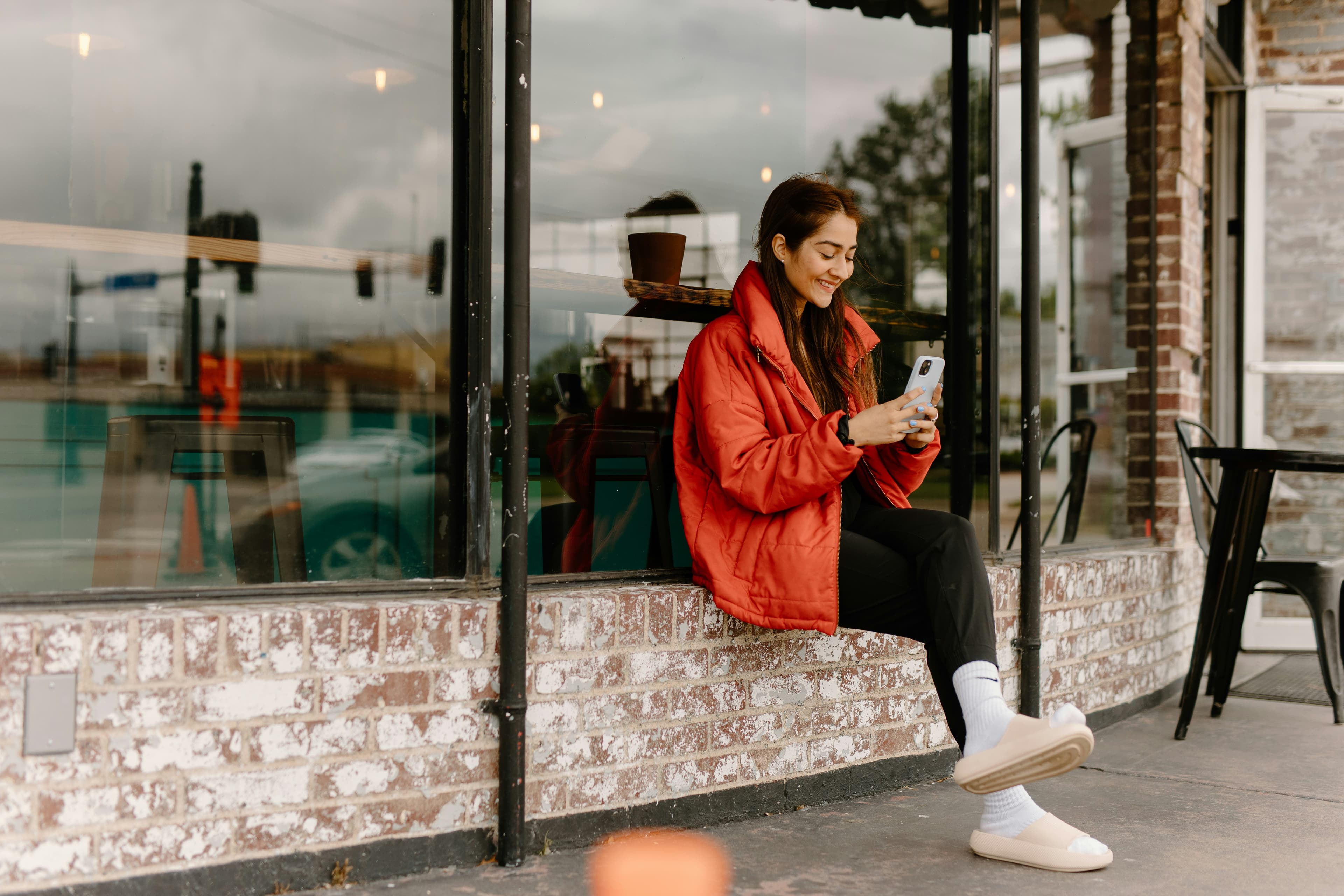 a woman sitting on a window sill looking at her cell phone