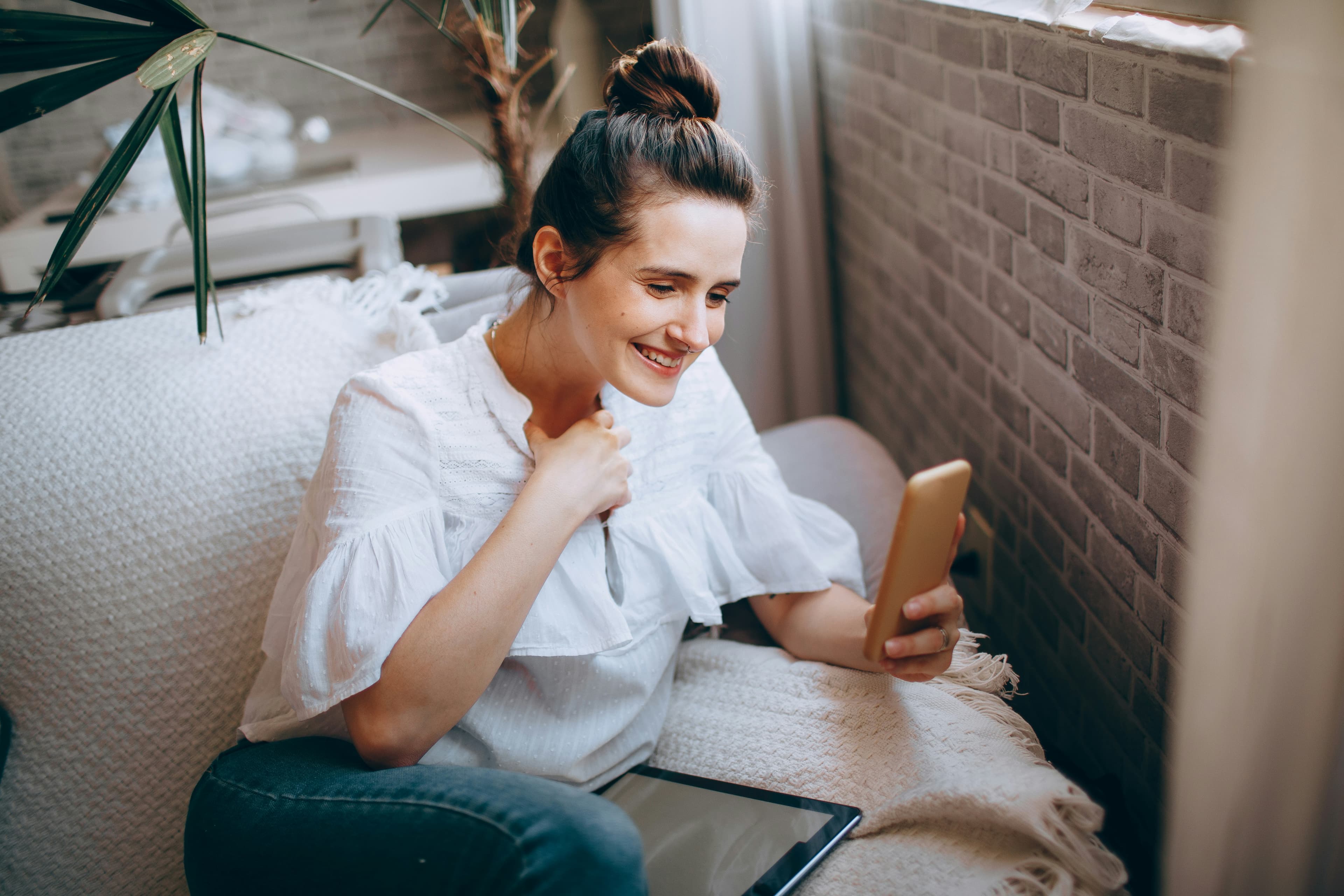Woman in white crew neck t-shirt and blue denim jeans sitting on white sofa