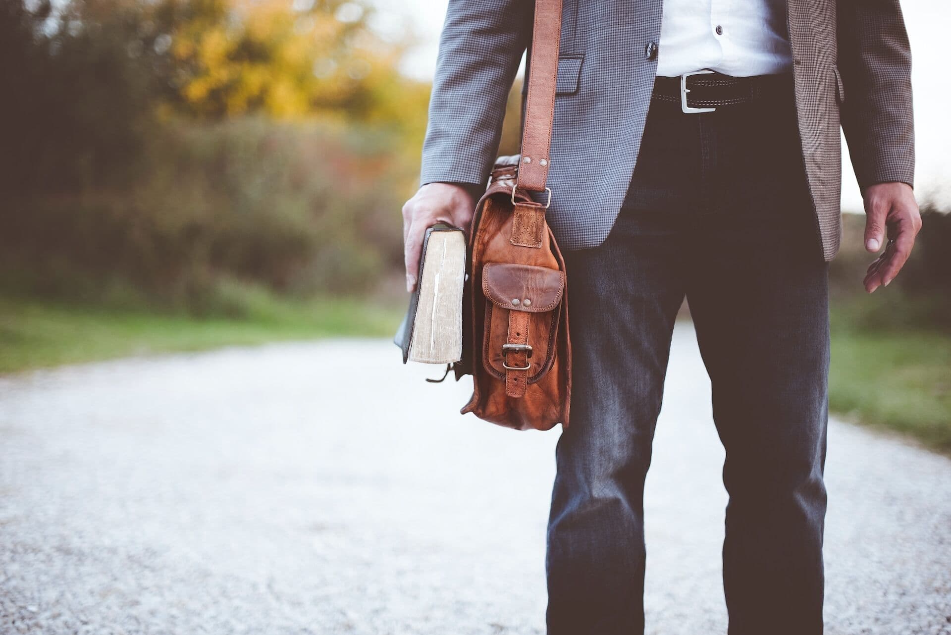 Man holding book on road during daytime