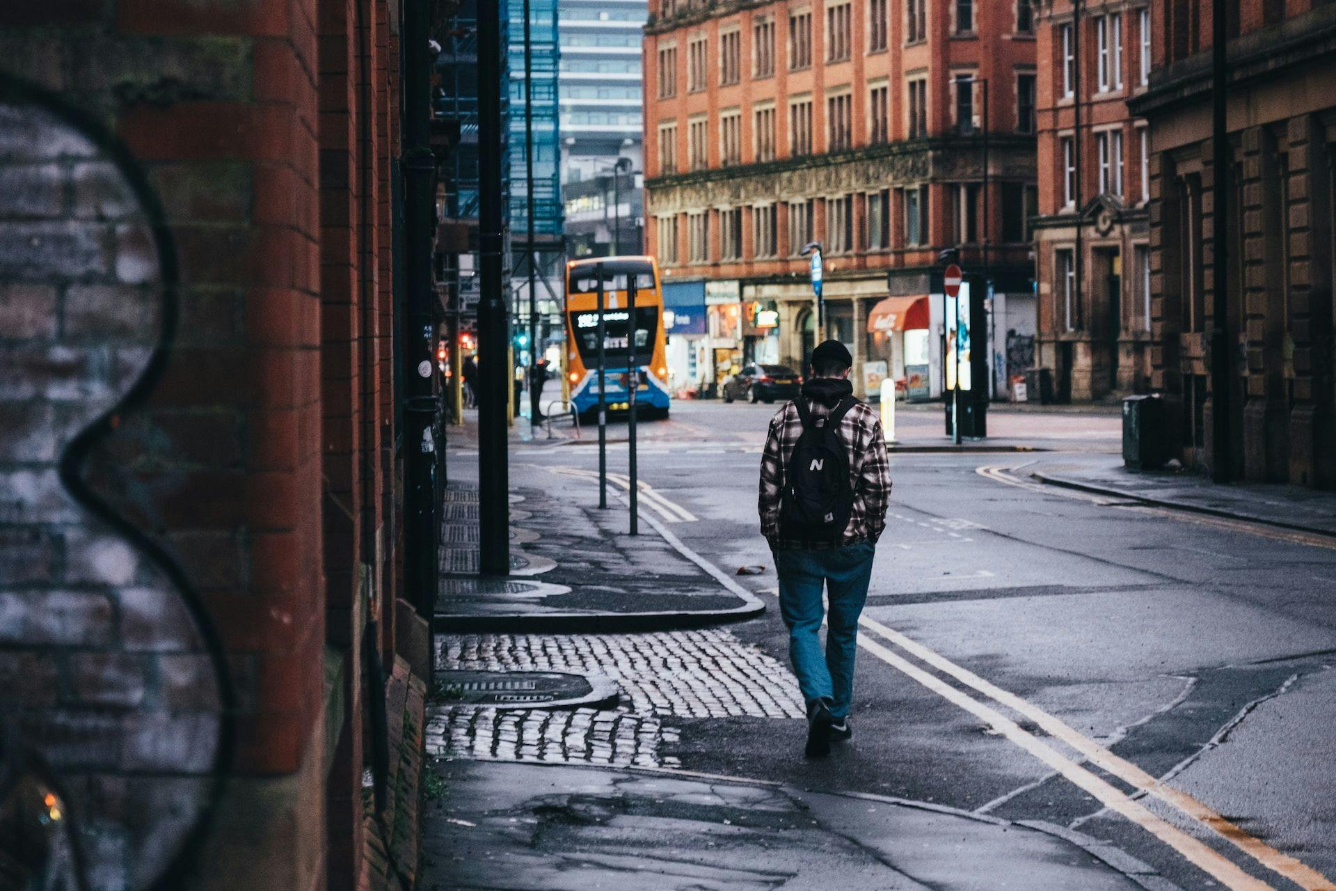 A man walking down a street next to tall buildings